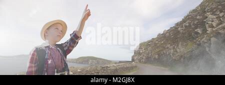 Travelling boy pointing in front of landscape Stock Photo