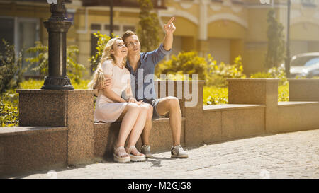 Guy hugging girlfriend on date, showing something in air, young couple in love, stock video Stock Photo