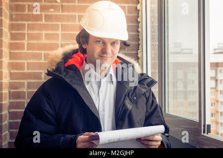 Portrait of an architect builder studying layout plan of the rooms, engineer working with documents on construction site, building and home renovation, professional foreman at work. Soft focus, toned. Stock Photo