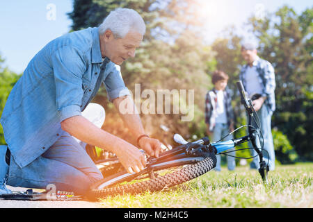 Thoughtful grandfather fixing bike of his little grandchild Stock Photo