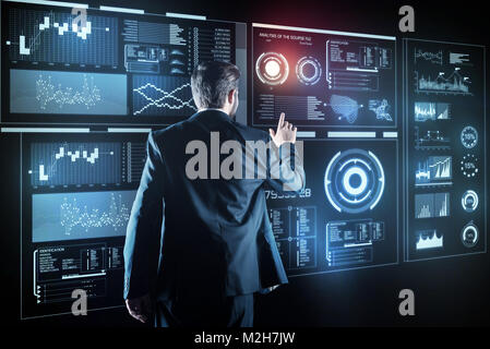 Clever programmer looking calm while touching the transparent screen Stock Photo