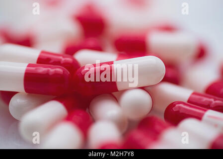 Close up of red and white capsule pills, pharmaceuticals, medicine, drugs or vitamin supplements. High key lighting and shallow depth of field. Stock Photo
