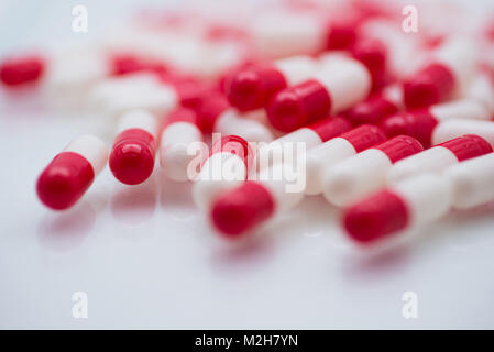 Close up of red and white capsule pills, pharmaceuticals, medicine, drugs or vitamin supplements. High key lighting and shallow depth of field. Stock Photo