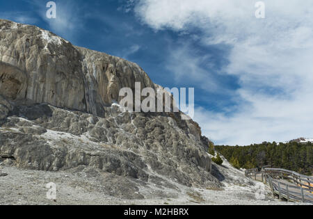 Grey streaked rock is left behind when the hot mineral spring water shifts course as seen in this tall cliff. Stock Photo
