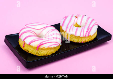 Two fresh round donuts on black plate Stock Photo