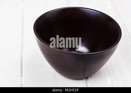 Brown ceramic bowl on white wooden background Stock Photo