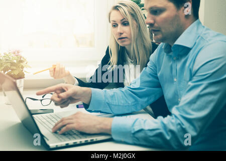 man and woman working together in office. discussing something on laptop Stock Photo