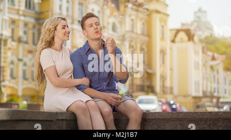Guy in love making soap bubbles, girlfriend in love sitting next to him, date, stock video Stock Photo