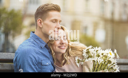 Man in love hugging beloved girlfriend, happy young lady holding nice flowers, stock video Stock Photo