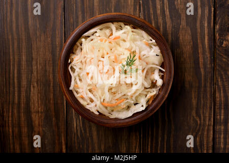 Sauerkraut with carrots in bowl. Marinated cabbage on wooden table. Top view, flat lay food Stock Photo