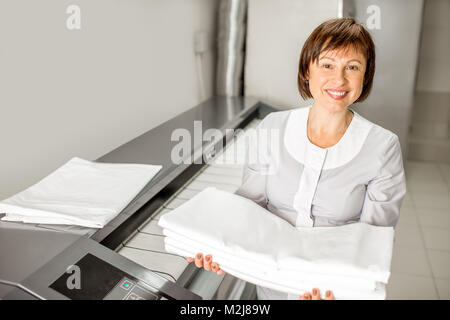 Laundress working with ironing machine Stock Photo