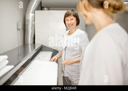 Laundress working with ironing machine Stock Photo