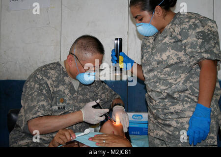 Army Reserve dentist, Maj. George Wan from Los Angeles, prepares a Salvadorian patient for a tooth extraction while Army Reserve dental technician, Spc. Nancy Cardenas from Lancaster, Calif.,  assists.  Members of the 185th Dental Company from Garden Grove, Calif., participated in a 15 day medical readiness exercise providing dental services to the citizens of the San Vicente area.  - Photo by Army Maj. Wendy Rodgers 349th Medrete in Tepetitan (63 of 78) by 807MCDS Stock Photo