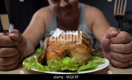 Fat man preparing to eat greasy fried chicken, holding knife and fork, close-up, stock footage Stock Photo