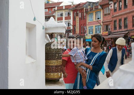 Mother with daughter and son. Son spinning the prayer wheel for good luck. At the largest stupa in Kathmandu Nepal Stock Photo