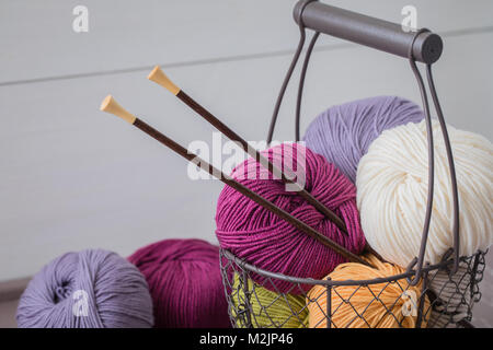 Colorful spring wool yarn in an iron basket with wooden knitting needles. With a copyspace Stock Photo