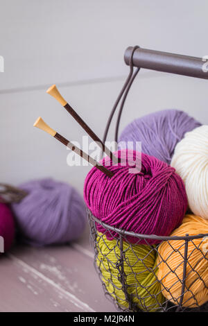 Colorful spring wool yarn in an iron basket with wooden knitting needles. With a copyspace Stock Photo