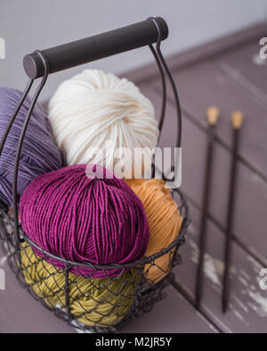 Colorful spring wool yarn in an iron basket with wooden knitting needles. With a copyspace Stock Photo