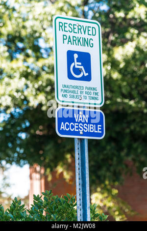 Vertical shot of a handicapped parking sign with a 15 mile per hour sign below it.  Out of focus trees and a building in the background. Stock Photo