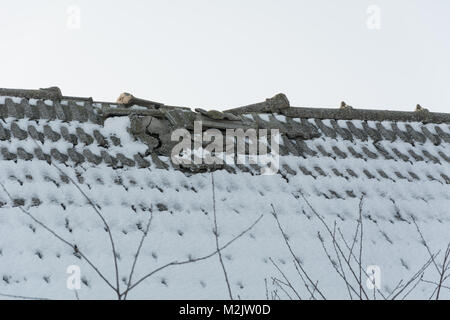 A broken tiled roof covered with snow Stock Photo