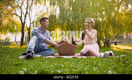 Happy couple unpacking wine bottle from picnic basket, wonderful rest together, stock footage Stock Photo
