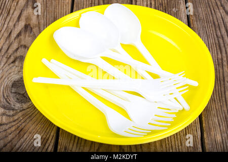 Plastic disposable tableware on wooden table Stock Photo