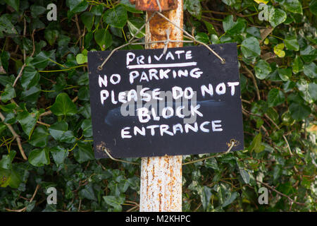 A polite no parking request hanging on a cast iron post at the entrance to a private dwelling Stock Photo