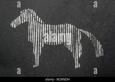 A sign of zebra crossing in a shape of zebra horse drawn on a asphalt pavement Stock Photo
