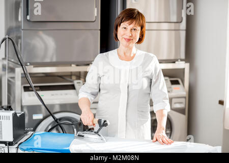 Senior washwoman ironing in the laundry Stock Photo