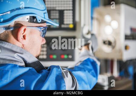 Computer Numerical Control Lathe Machine Operator. CNC Caucasian Technician.MEtworking Industry Equipment. Stock Photo