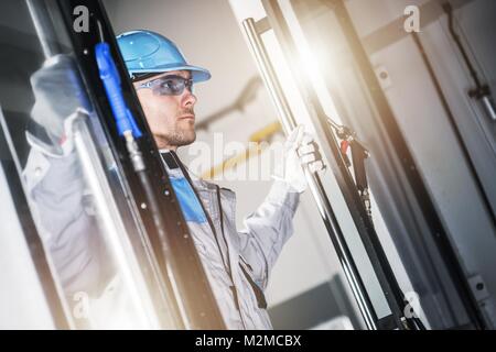 Caucasian CNC Technician Taking Look Inside the Modern CNC Machine. Metalworking Industry Concept. Stock Photo