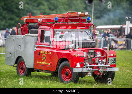 Side view of vintage Land Rover fire brigade vehicle parked on the grass, Masham, North Yorkshire, UK Stock Photo