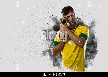 Brazilian soccer player coming out of a blast of smoke. celebrating with a trophy in his hand. Stock Photo