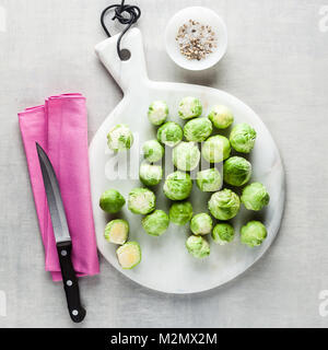 Brussels sprout on a white marble cutting board and knife. spices and food ingredients. cooking healthy food Stock Photo