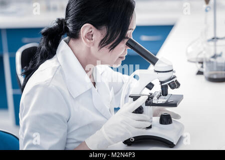 Concentrated scientist examining sample under microscope Stock Photo
