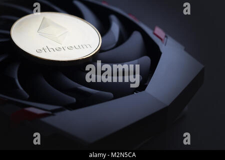 cryptocurrency mining concept with one golden Ethereum coin on top of a computer performant video card black fan Stock Photo