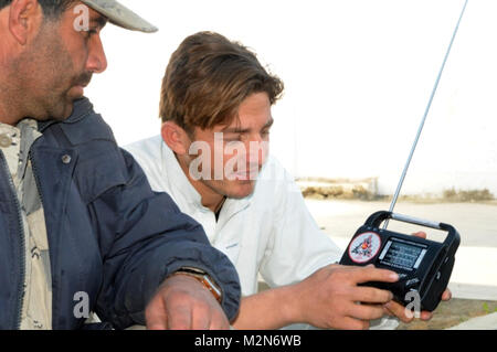 NANGARHAR, Afghanistan  (Jan. 18, 2010) -  100118-A-3421S-229: SHINWAR PROVINCE, Afghanistan – Searching for a the new Shinwar district radio station a young Afghan, with the help of an Afghan Border Police officer, manipulates the dial of a hand-cranked radio distributed by Afghan national and coalition security forces.  The radios and new radio station are part of a media information initiative sponsored by the International Security Assistance Force’s [ISAF] counterinsurgency program. Georgia Army National Guardsmen of 1st Squadron, 108th Cavalry Regiment, Task Force Mountain Warrior have o Stock Photo