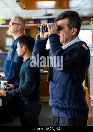 Ship's crew on bridge sailing passenger ship Ocean Adventurer; carries alpine mountaineering skiers to Antarctica Stock Photo