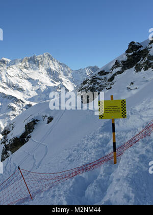 Winter scenes in the snowsports resort of Zinal in Valais canton of Switzerland and showing the avalanche warning sign at start of the free ride area. Stock Photo