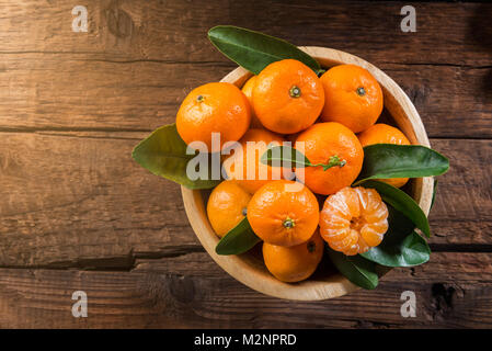 Delicious and beautiful mini Tangerines with leaves in the wooden bowl Stock Photo