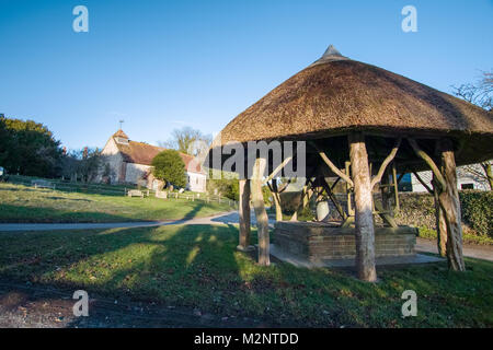 St Peters Church and thatched village well. East Marden, West Sussex, UK Stock Photo