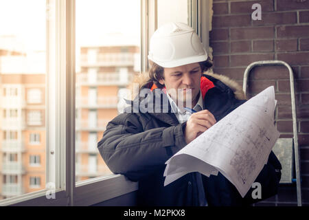 Young engineers using pen point to the blueprint paper to examine the structure of the house before presenting it at the conference. Architecture desi Stock Photo