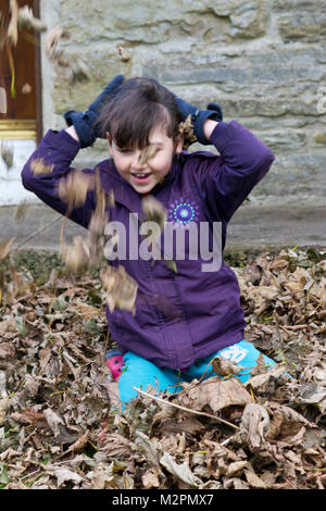 Young girl playing with autumn leaves Stock Photo