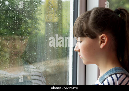 Sad child looking through window Stock Photo