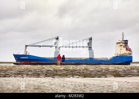 Swinoujscie, Poland - January 28, 2018: People watch Langeoog cargo ship leaving the port of Swinoujscie on a cloudy winter day. Stock Photo