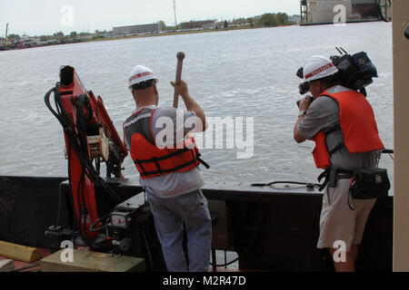 Deckhand James Jarrell secures a large piece of debris prior to bringing it safely onboard the Corps Vessel Harrell in the Elizabeth River as Art Kohn, from WAVY-TV 10, looks on. Hampton Roads Drift Removal Program, which takes place all year long, ensures the federal navigation channel is safe for commercial shipping and boaters and is even more vital shortly after large coastal storms hit the area.   (U.S. Army Photo/Patrick Bloodgood) 110830-A-OI229-006 by norfolkdistrict Stock Photo