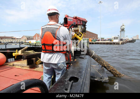 Deckhand James Jarrell uses a crane to remove debris from the Elizabeth River a few days after Hurricane Irene came through the area. The Hampton Roads Harbor Debris Removal Program, which takes place all year long, ensures the federal navigation channel is safe for commercial shipping and boaters.  (U.S. Army Photo/Patrick Bloodgood) 110830-A-OI229-024 by norfolkdistrict Stock Photo