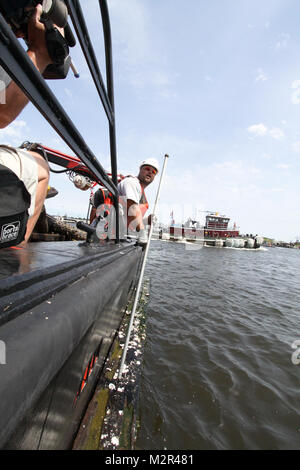 Deckhand James Jarrell secures a large piece of debris alongside the Corps Vessel Harrell in the Elizabeth River days after Hurricane Irene blew through the area. The Hampton Roads Harbor Debris Removal Project, which takes place all year long, ensures the federal navigation channel is safe for commercial shipping and boaters.  (U.S. Army Photo/Patrick Bloodgood) 110830-A-OI229-044 by norfolkdistrict Stock Photo