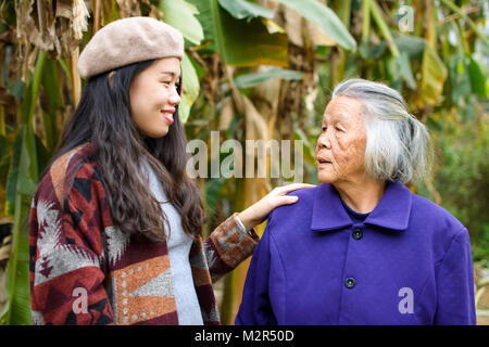 Asian girl spending time outdoors with her grandma in green tropical environment Stock Photo