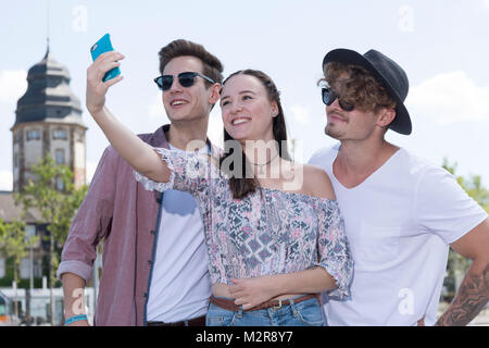 Two young men and a girl close Smartphone in the town, Selfie, semi-portrait Stock Photo